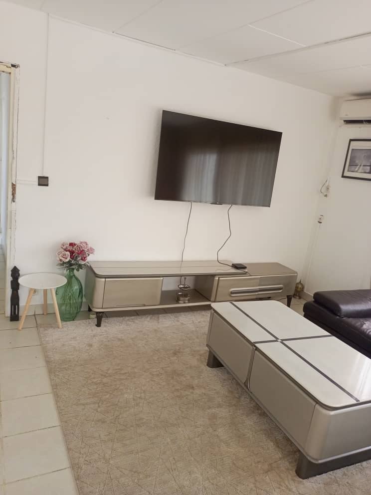 Salon avec télévision et canapé chez Nelye
